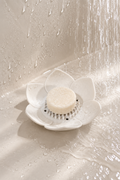 Porte-savon lotus en silicone utilisé sous la douche avec un galet de douche