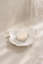 Porte-savon lotus en silicone utilisé sous la douche avec un galet de douche